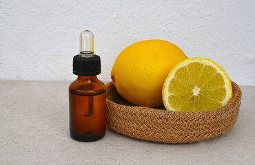 Lemon essential oil in a glass bottle with fresh lemon fruits on light background. Aromatherapy, wellness, body care or spa ingredient concept.Selective focus.