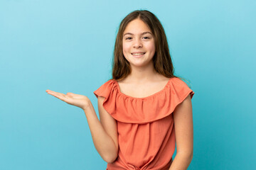 Little caucasian girl isolated on blue background holding copyspace imaginary on the palm to insert an ad