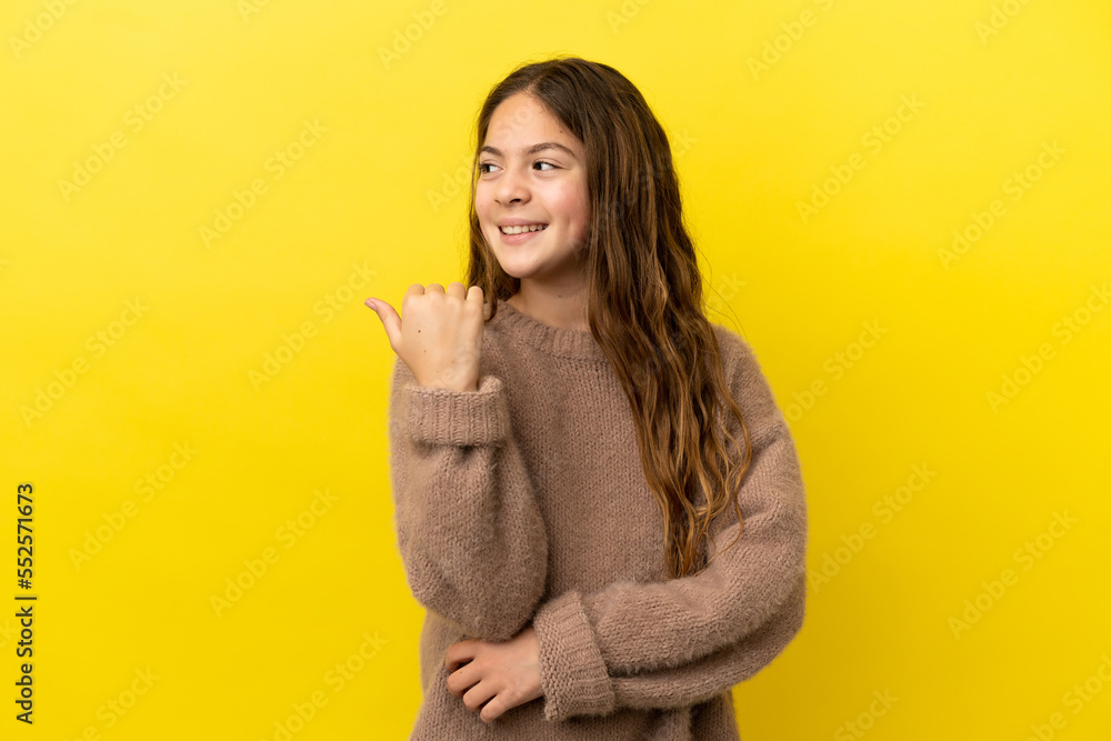 Poster Little caucasian girl isolated on yellow background pointing to the side to present a product