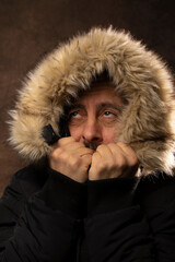 portrait d'un homme portant un gros manteau d'hiver et qui grimace car il a très froid