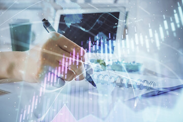 Fototapeta na wymiar Financial forex graph drawn over hands taking notes background. Concept of research. Multi exposure