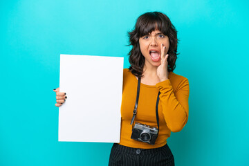 Young photographer latin woman isolated on blue background holding an empty placard and shouting