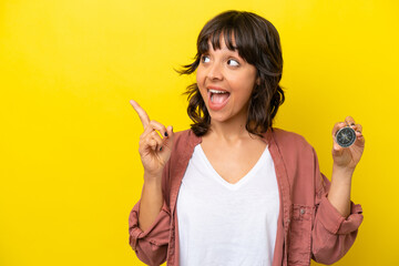 Young latin woman holding compass isolated on yellow background intending to realizes the solution while lifting a finger up