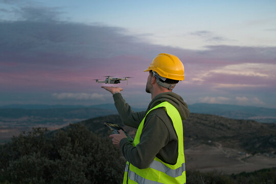 Working man directs a drone at sunset