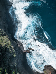 Aerial view of some cliffs over the ocean. The strong waves of the sea break against the rocks. Tenerife, Spain