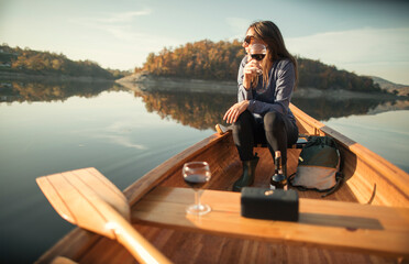 Young woman enjoy outdoors in canoe with glass of red wine