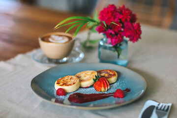 Cottage cheese pancakes or syrniki with raspberry jam on a green plate
