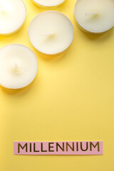 Fototapeta na wymiar Pink paper with text millennium and white candles on yellow tabl