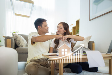 Obraz na płótnie Canvas Asian couple in home or house. Include increasing graph, laptop, calculator and document on table. To bump punch with concept for market price, house value, loan, finance, real estate and property. 
