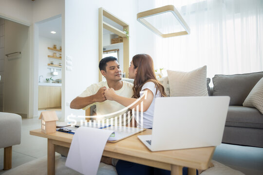 Asian couple in home or house. Include increasing graph, laptop, calculator and document on table. To bump punch with concept for market price, house value, loan, finance, real estate and property.

