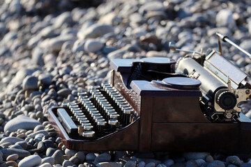 Close-up of a vintage typewriter on the beach by the sea