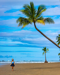 A beautiful girl in a short skirt walks under palm trees on a tropical beach in Costa Rica; marino ballena national park near quepos 