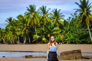 Fototapeta na wymiar a lone beautiful girl in a skirt walks along a tropical beach with palm trees in marino ballena national park in costa rica; relaxing on a paradise beach in costa rica