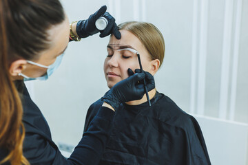 Young woman during professional eyebrow mapping procedure before permanent makeup - obrazy, fototapety, plakaty