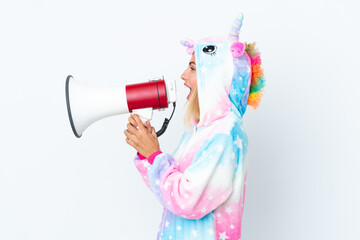 Blonde Uruguayan girl wearing a unicorn pajama isolated on white background shouting through a...