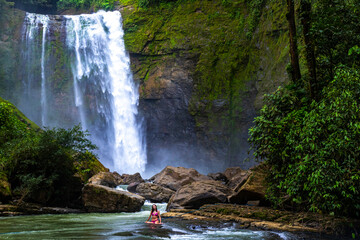 A beautiful girl in a pink bikini swims in a rushing river below the eco chontales waterfall in...