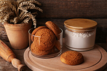 Fototapeta na wymiar Cookies, flour and wheat spikes on wooden table