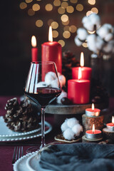 Rustic table decor for Christmas or New Year family dinner. Centrepiece with red candle, dry orange, cone, cinnamon, anise. Zero waste eco-friendly home. Cozy atmosphere, dark background. Close up