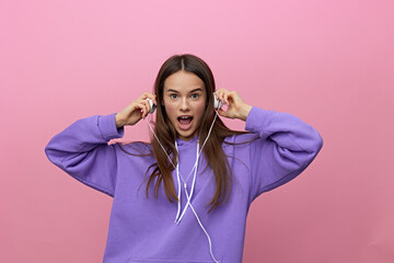 a funny, funny, beautiful woman stands in purple clothes on a pink background wearing headphones and screams loudly while looking at the camera