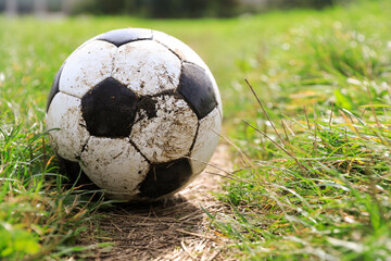 Dirty soccer ball on green grass outdoors, space for text