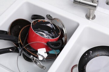 Messy pile of dirty kitchenware in sink, above view