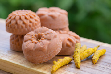  Round orange soap in the form of flowers with turmeric on a green background