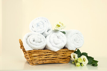 Soft folded towels and flowers on white table