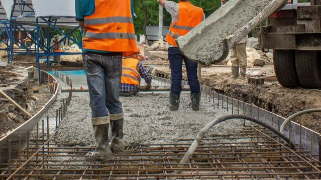 Concrete works in metal reinforcement for road construction with many workers in uniform, excavators and mixer machine timelapse. Reconstruction of tram tracks