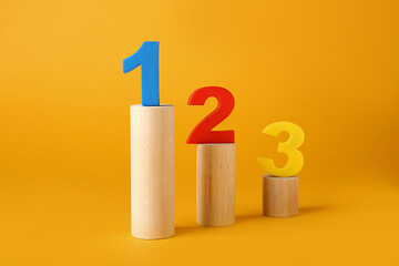Numbers on wooden blocks against pale orange background. Competition concept