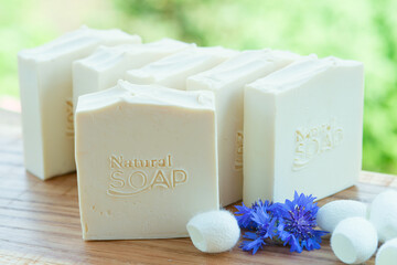  White handmade soap with blue flowers and silk cocoons on a green background