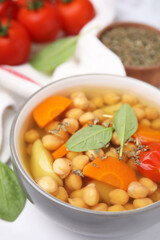 Tasty chickpea soup in bowl and spices on white table