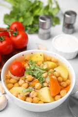 Tasty chickpea soup in bowl served on light grey table