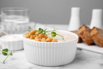 Tasty chickpea soup in bowl on white marble table, closeup