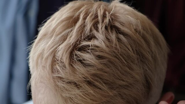 A man straightens his blond-dyed hair with his hand, close-up