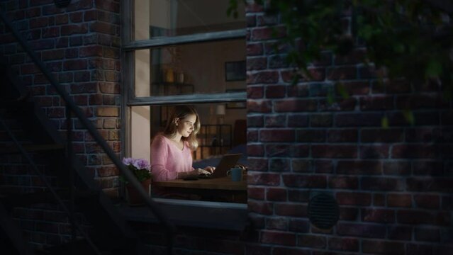 Portrait of Young Woman Using Laptop at home at Night. Female Working on a Creative Job Position at an Advertising Company. Focused Manager Communicating with Colleagues, Writing a Business Plan.