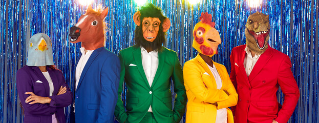 Group of strange people at costume party. Team of funny confident people wearing different bright colourful stylish suits and surreal bizarre carnival animal masks standing together on blue background - obrazy, fototapety, plakaty