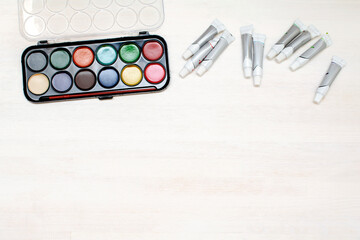 Watercolor oil paints in raw. Creativity creation process. Artist's stuff on white wooden table,blank copy space im middle.Top view Flatlay of drawing supplies