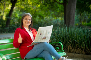 Obraz premium Senior Indian woman reading newspaper at park.