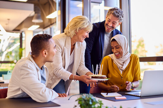Staff Celebrating Birthday Of Female Colleague Wearing Headscarf In Office With Cake