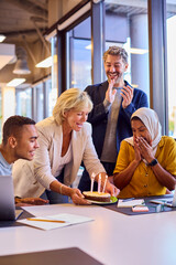 Staff Celebrating Birthday Of Female Colleague Wearing Headscarf In Office With Cake
