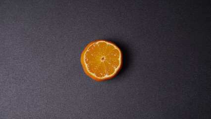 Festive decoration with sliced ​​tangerine and star on a black background. Juicy tangerine with drops of juice and star anise