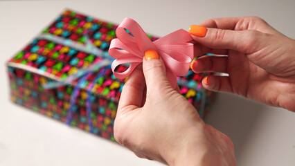 The process of wrapping a gift with women's hands for a birthday in colored gift paper with the inscription 