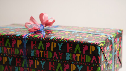 The process of wrapping a gift with women's hands for a birthday in colored gift paper with the inscription "happy birthday"