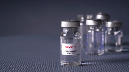 Ampoules of coronavirus vaccine. Concept, vaccine COVID-19 in ampoules and syringe with needle, on gray background in hospital.