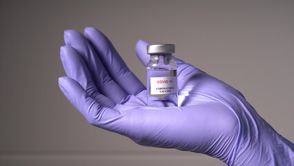 Transparent ampoule with medication in the hands of a nurse in medical gloves. Vaccine from...