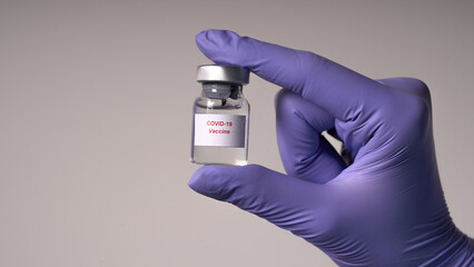 Transparent ampoule with medication in the hands of a nurse in medical gloves. Vaccine from COVID-19.