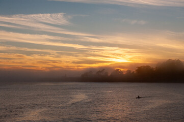 Silhoutte of a person in a kayak peddling in the Santa Cruz bay during sunset.