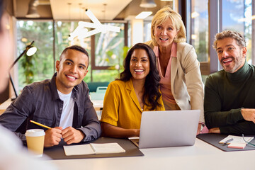 Obraz premium Multi-Cultural Business Team Meeting Around Laptop In Modern Office