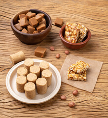 Typical brazilian candies over wooden table. Doce de leite or dulce de leche, pe de moleque and pacoca