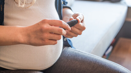 Close-up Of Pregnant Woman using lancing device for blood glucose monitoring